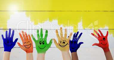 Painted hands faces with yellow paint wood background