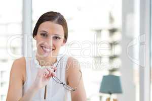 Happy business woman holding her glasses against white blurred background