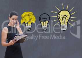 Woman on phone standing next to light bulbs with crumpled paper ball in front of blackboard