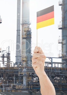 Hand holding German flag in front of industrial factory power plant