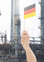 Hand holding German flag in front of industrial factory power plant