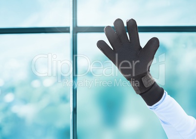 Hand wearing glove in front of window