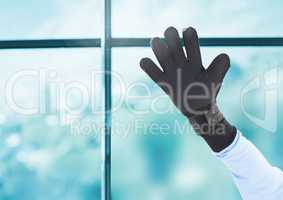 Hand wearing glove in front of window