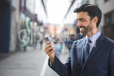 Happy business man using the phone against street background