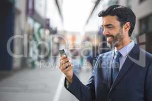 Happy business man using the phone against street background