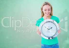 Woman holding clock in front of green background