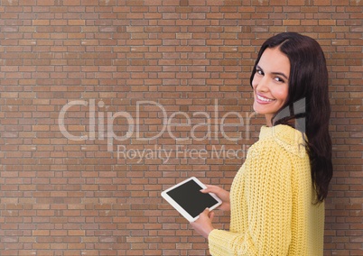 Happy business woman using a tablet against brick wall background