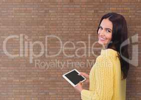 Happy business woman using a tablet against brick wall background