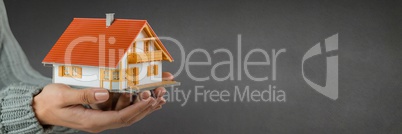 Woman holding a house against grey background as concept of insurance