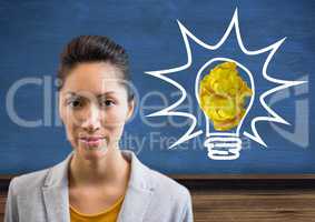 Woman standing next to light bulb with crumpled paper ball in front of blackboard