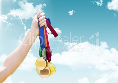 Hand holding medals in front of sky