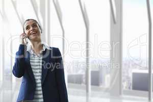 Happy business woman talking on the phone against building background