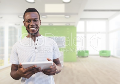 Happy business man holding a tablet against office background