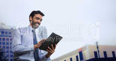 Happy business man using a tablet against city background