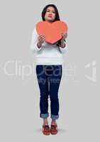 Full body portrait of woman standing and holding a heart cut out with grey background