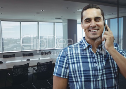 Happy business man talking on the phone against office background