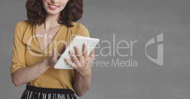Happy business woman using a tablet against grey background