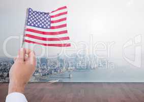 Hand holding American flag  in front of city