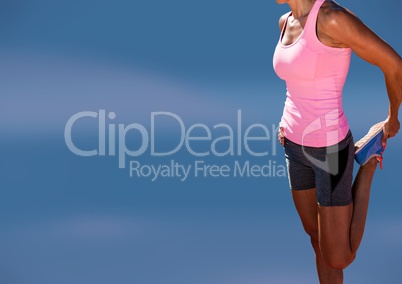 Athletic slim woman stretching leg in front of blue background