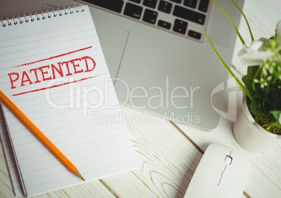 Patented text written on page with laptop and plant
