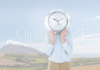 Person holding clock in front of nature landscape
