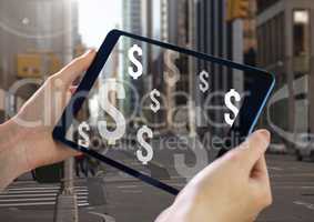 Holding tablet and Dollar icons over city