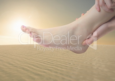 Hands holding foot in desert