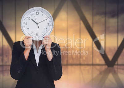 Woman holding clock in front of windows of city