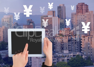 Holding tablet and Yen icons over city buildings