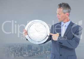 man holding clock in front of city