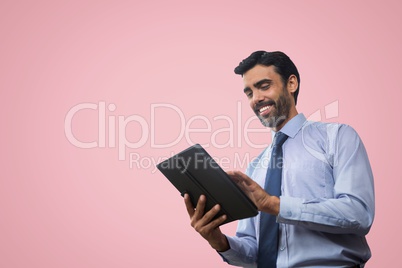 Happy business man using a tablet against pink background