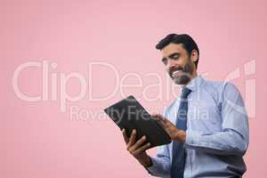 Happy business man using a tablet against pink background