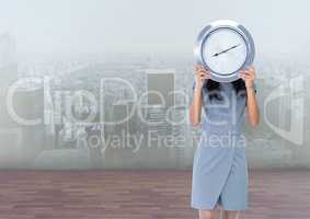 Woman holding clock in front of city