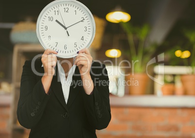 Woman holding clock in front of cafe