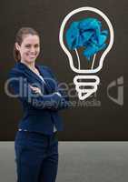 Woman standing next to light bulb with crumpled paper ball in front of blackboard