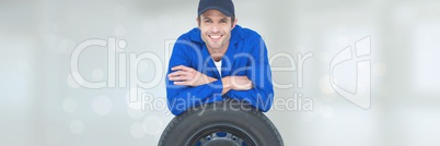Happy mechanic man supporting himself on a wheel