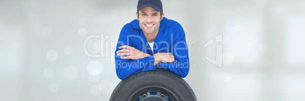 Happy mechanic man supporting himself on a wheel