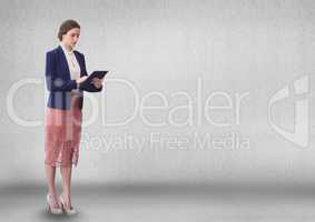 Business woman using a tablet against grey wall background