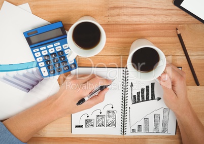 Drawing business charts in notepad with coffee and calculator