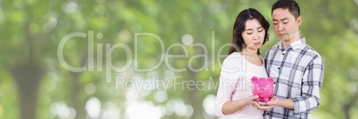 Couple holding a piggy bank against green background