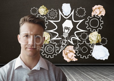 Man standing next to light bulb with crumpled paper balls in front of blackboard