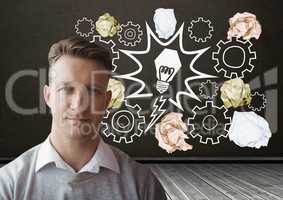 Man standing next to light bulb with crumpled paper balls in front of blackboard