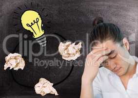 Man  next to light bulb with crumpled paper balls in front of blackboard