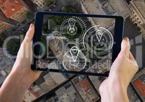 Holding tablet and City aerial view with marker location pointers