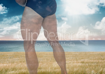 Strong man's muscular legs over sea landscape