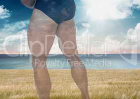 Strong man's muscular legs over sea landscape