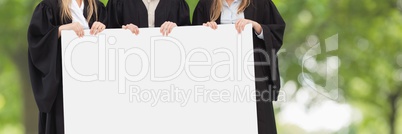 Graduated people holding a blank card against green blurred background