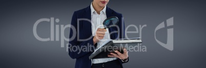 Woman with a magnifying glass against grey background as looking for an insurance concept