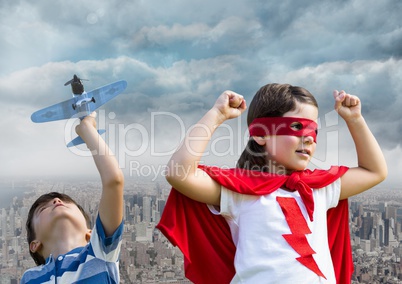 Superhero kids playing with toy plane over city
