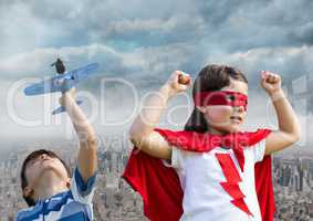 Superhero kids playing with toy plane over city